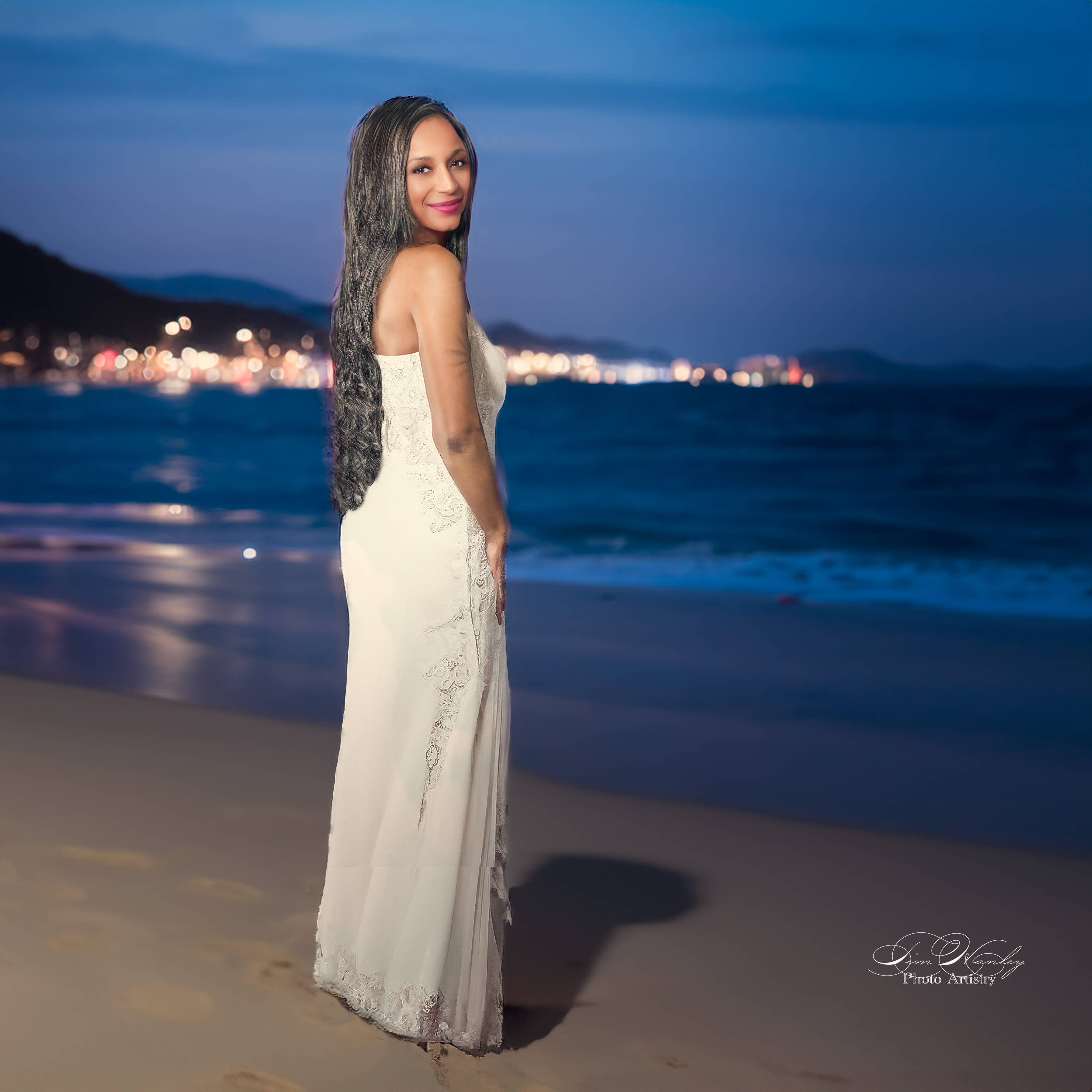Woman in embroidered gown on beach at night