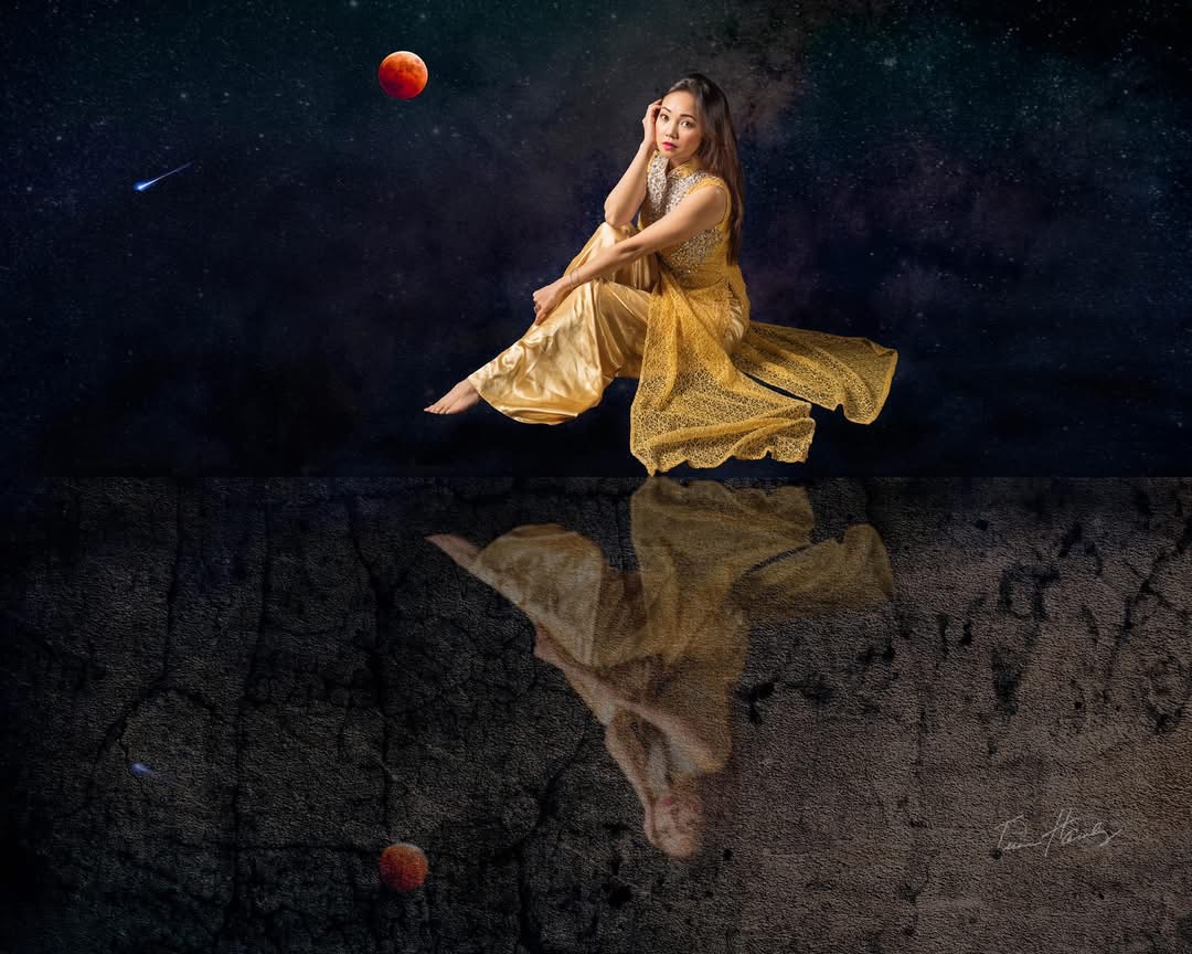Woman floating above cracked earth with moon