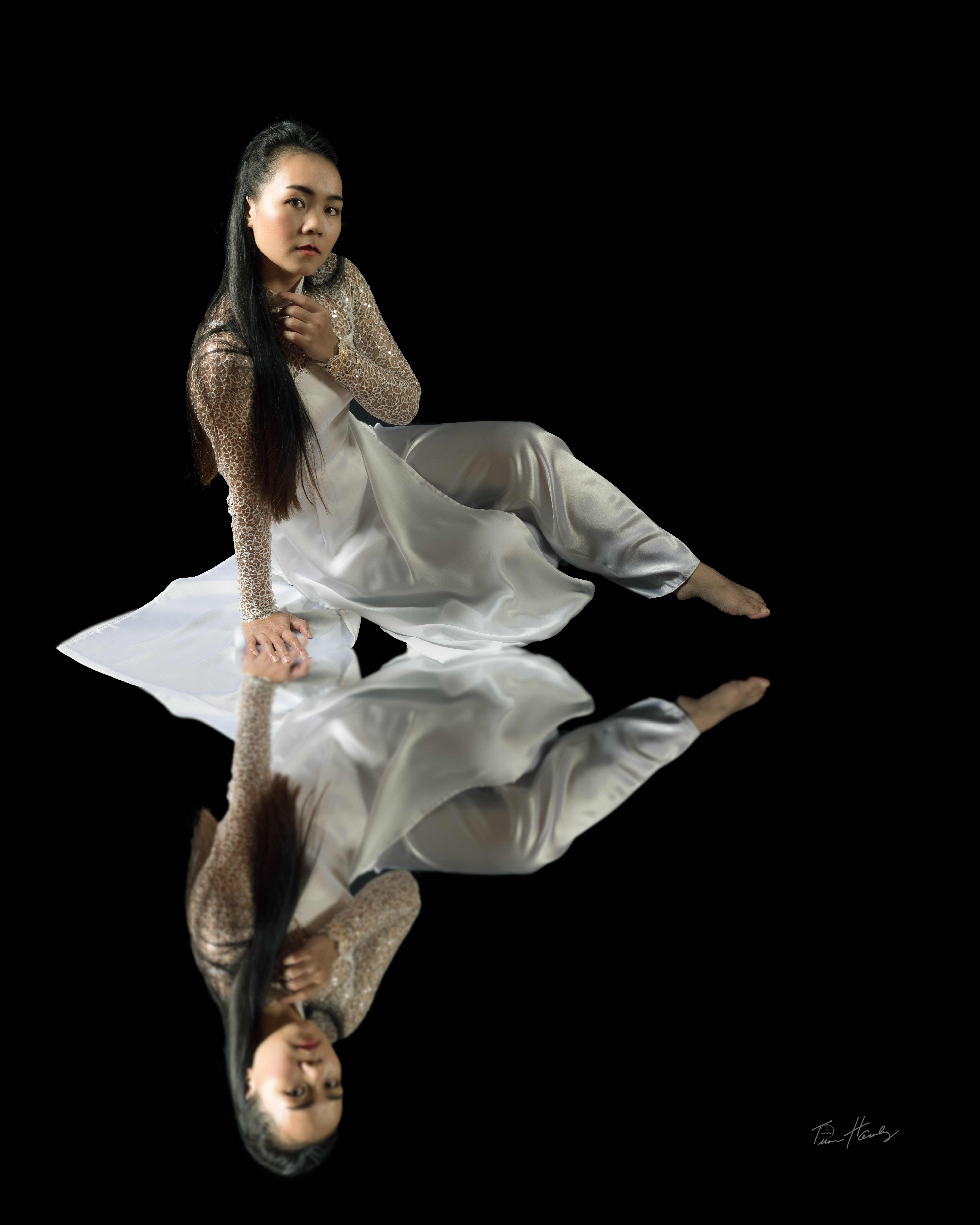 Woman in lace áo dài floating with full reflection below